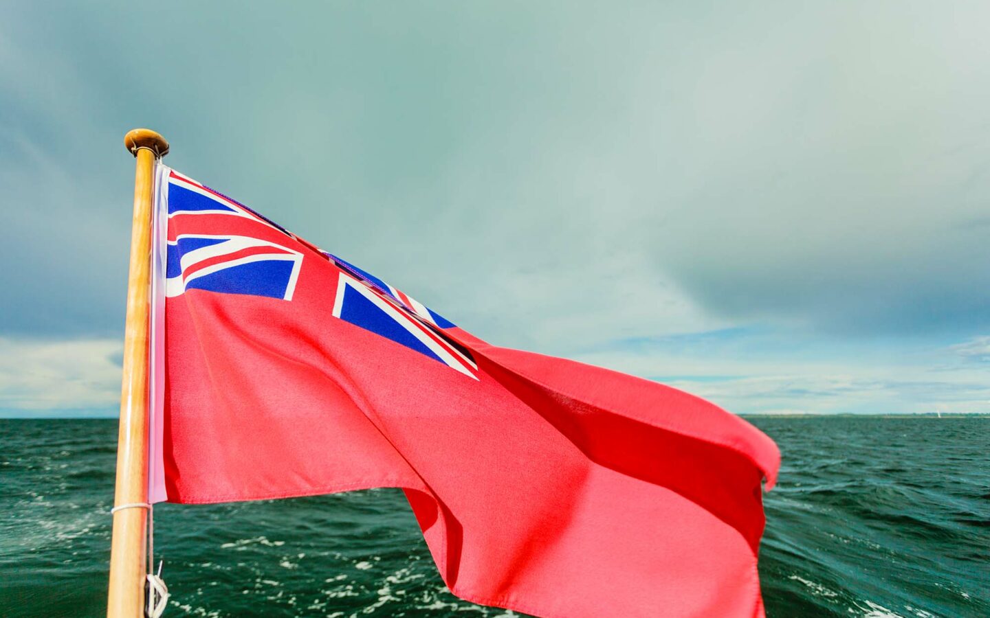 Red ensign flag flying on back of boat over the sea
