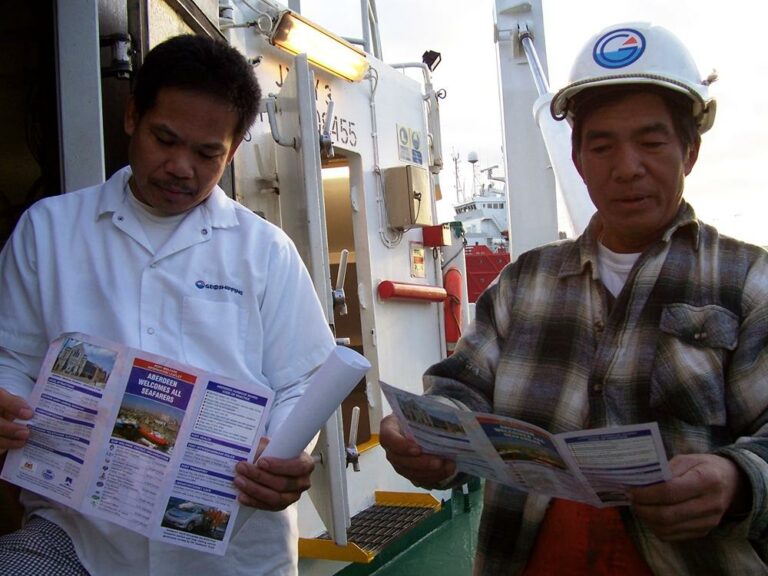Two seafarers reading the Aberdeen port information leaflet