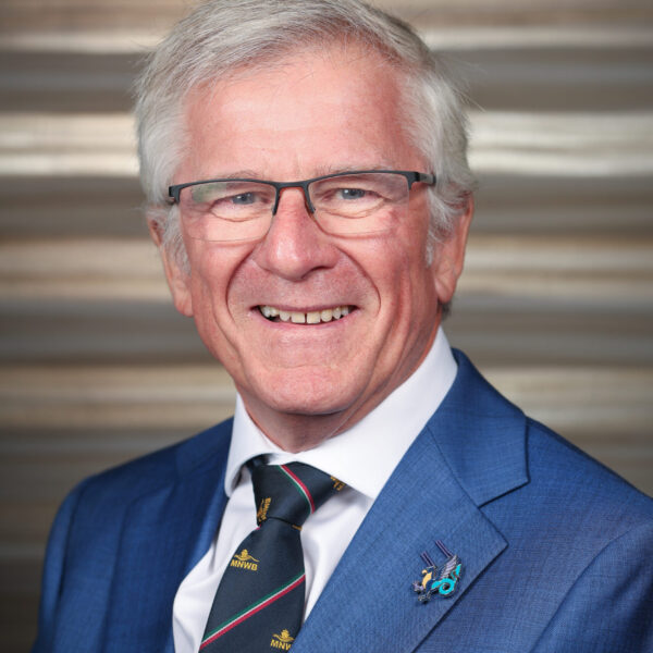 Portrait of a smiling man with grey hair and glasses in a blue suit